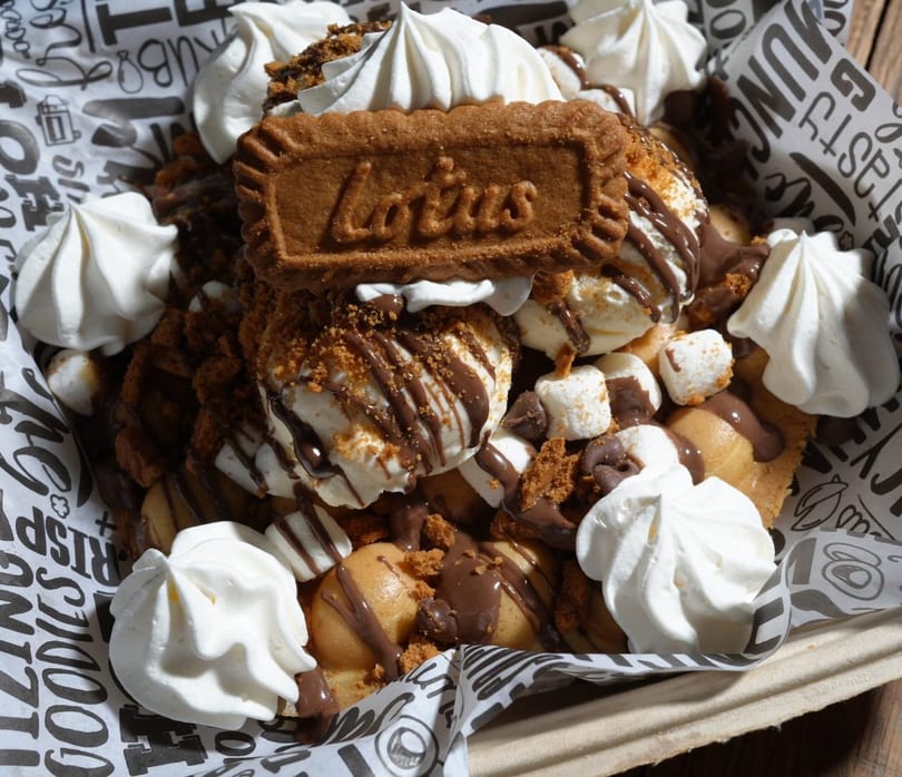 Bubble waffle dessert with ice cream, chocolate drizzle, marshmallows, whipped cream, and a Lotus Biscoff cookie.